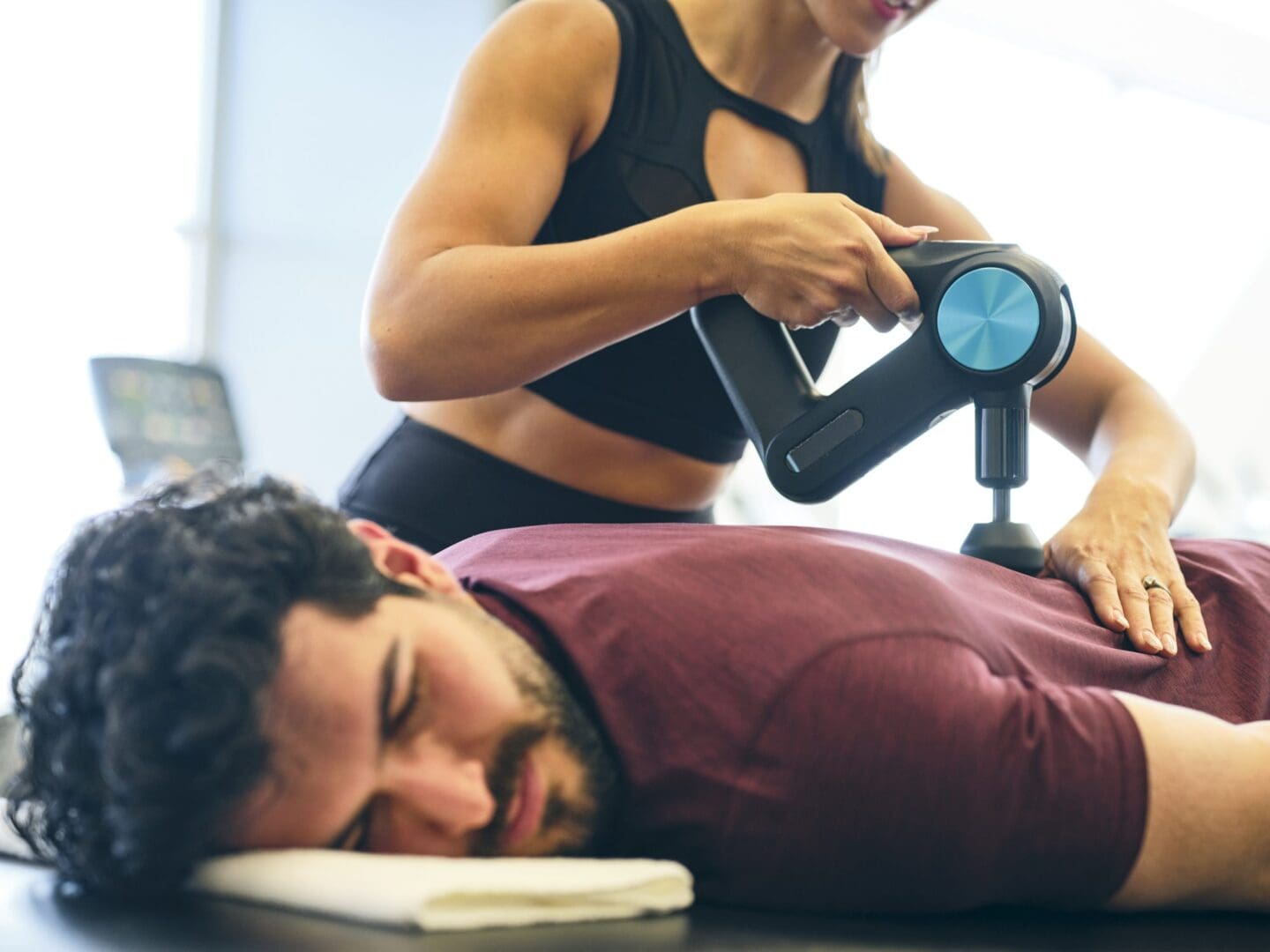 Person receiving massage with percussion device.