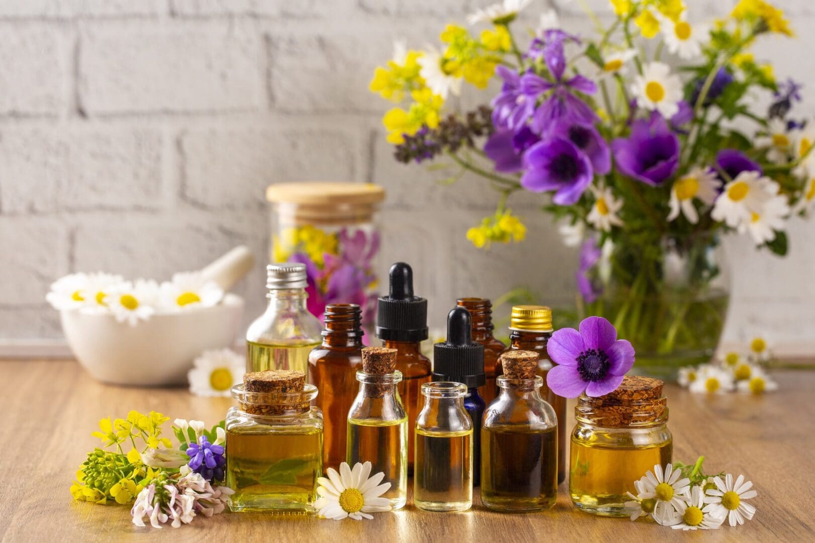 Essential oils with colorful flowers on table.