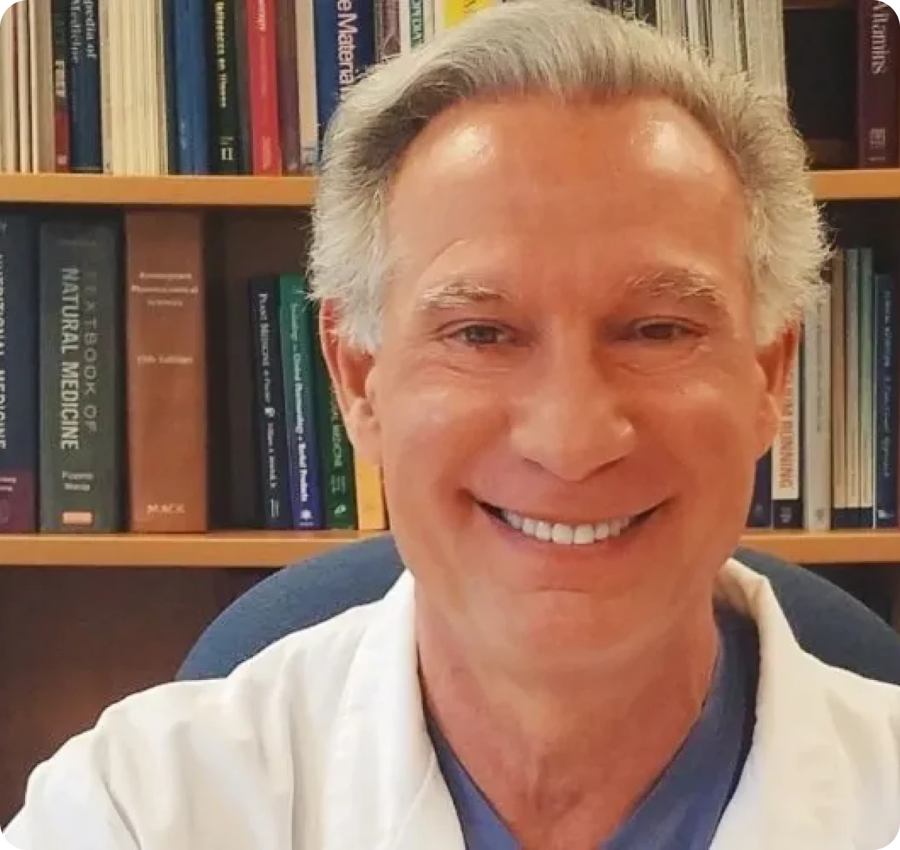 Smiling man in front of bookshelf.