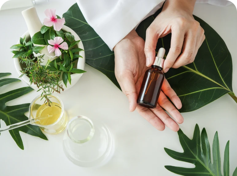 Hands holding essential oil bottle, botanical background.