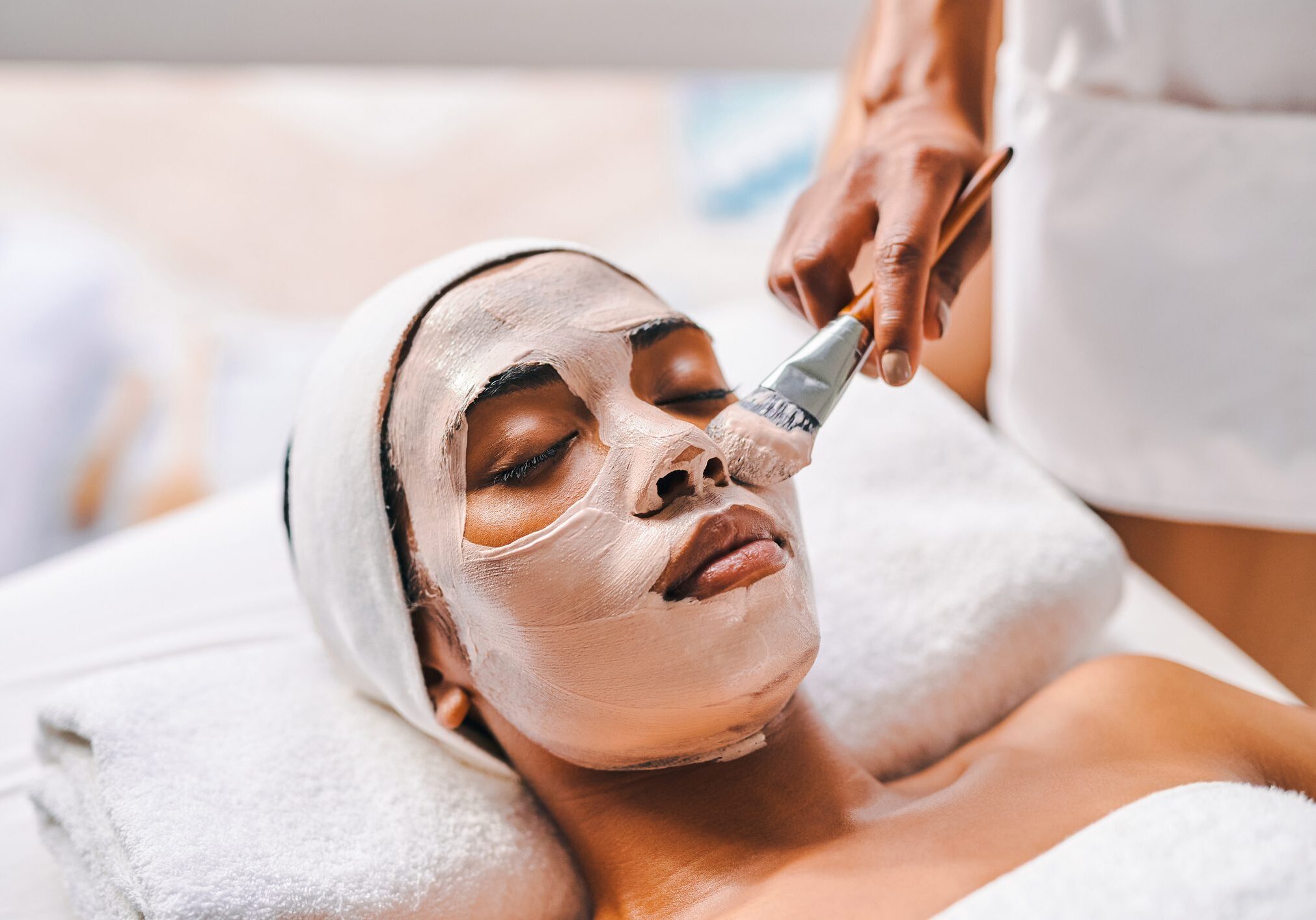 Woman receiving facial treatment with brush.
